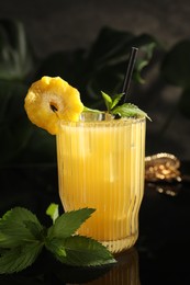 Photo of Tasty pineapple cocktail with mint on black mirror surface