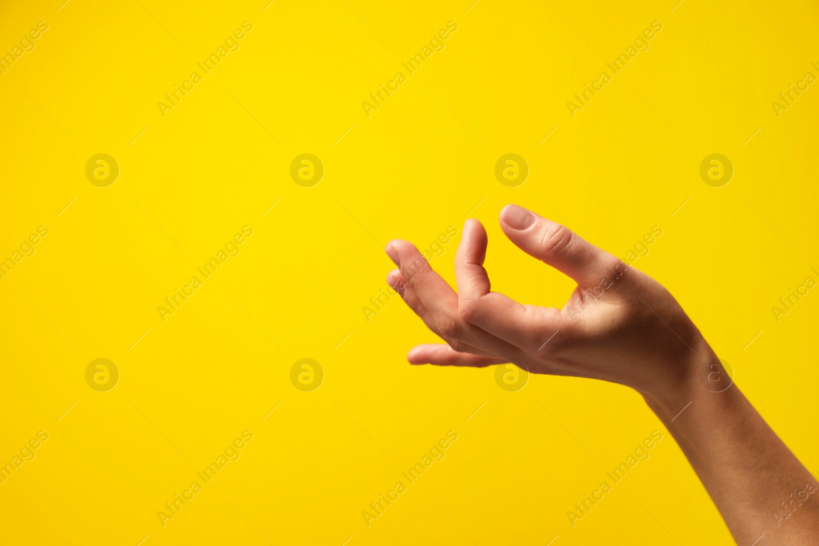 Photo of Woman holding something in hand on yellow background, closeup. Space for text