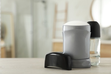 Photo of Male deodorants on wooden table in bathroom. Space for text