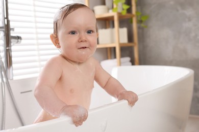 Photo of Cute little baby taking foamy bath at home, space for text