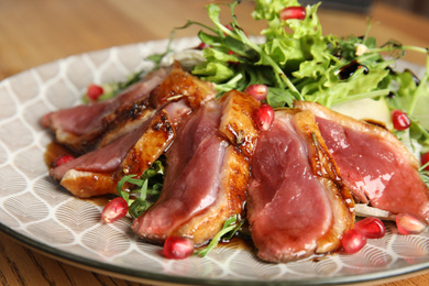 Photo of Delicious salad with roasted duck breast served on wooden table, closeup