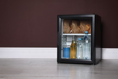 Photo of Mini bar filled with food and drinks near brown wall indoors, space for text