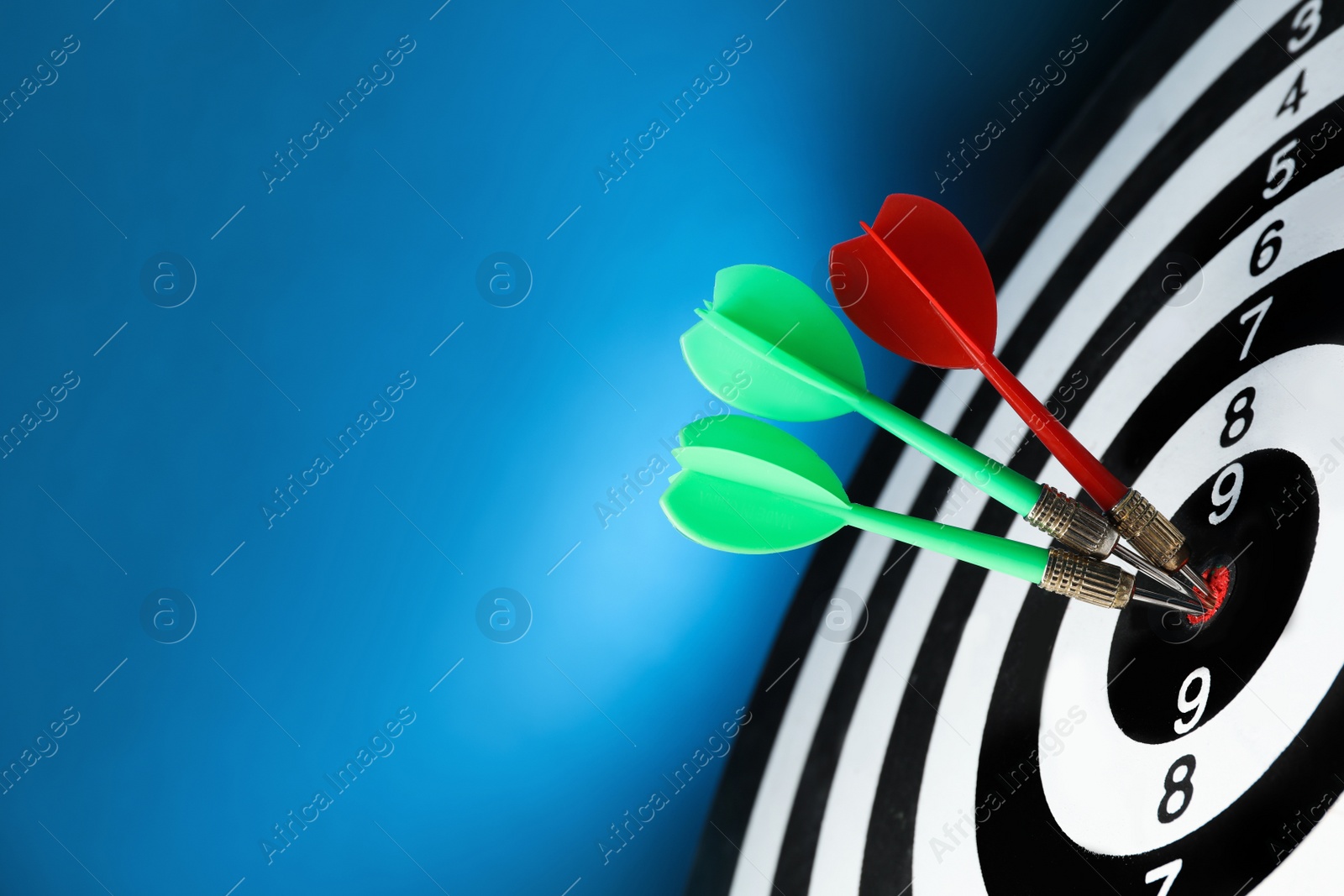 Photo of Arrows hitting target on dart board against blue background