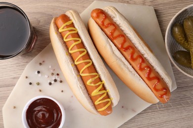 Photo of Tasty hot dogs with ketchup and mustard served on wooden table, flat lay