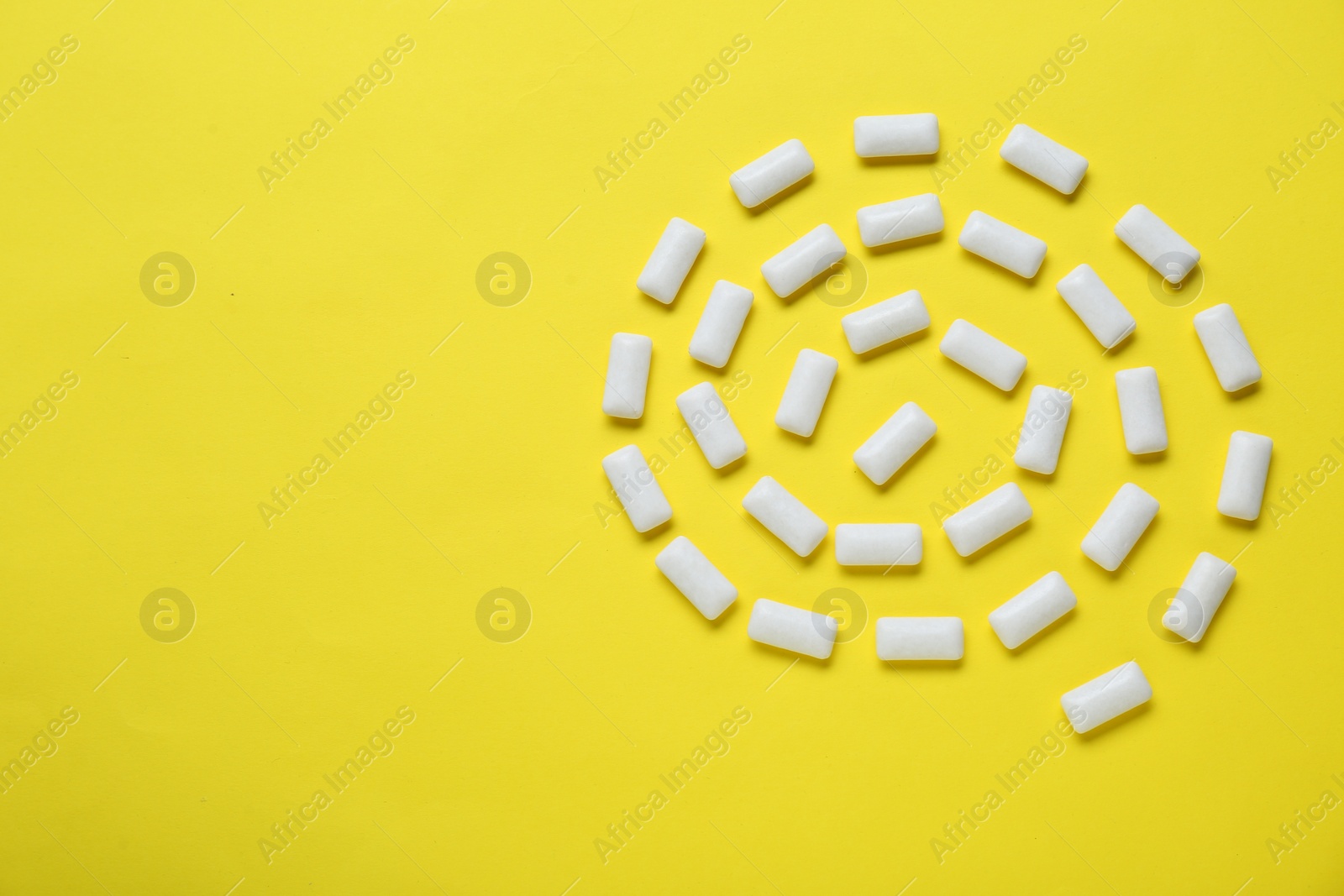 Photo of Tasty white chewing gums on yellow background, flat lay. Space for text