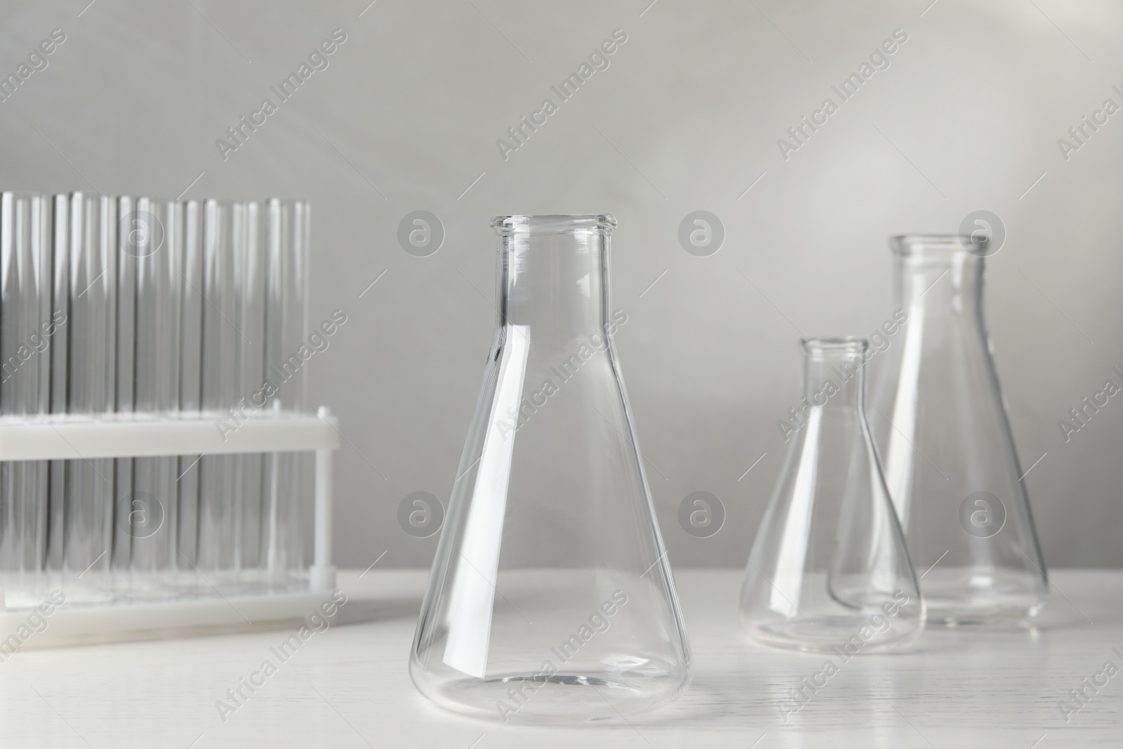 Photo of Set of laboratory glassware on white table against grey background