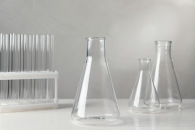 Photo of Set of laboratory glassware on white table against grey background