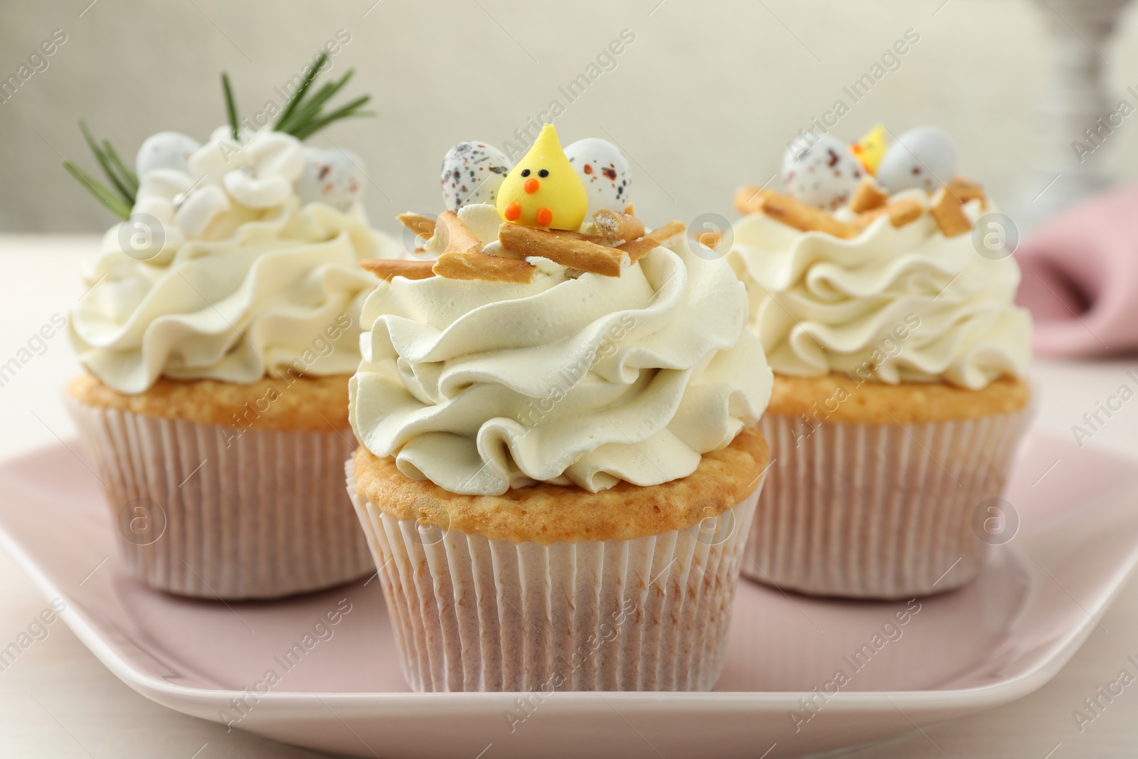 Photo of Tasty Easter cupcakes with vanilla cream on light table, closeup