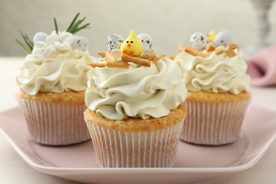 Tasty Easter cupcakes with vanilla cream on light table, closeup