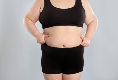 Photo of Overweight woman touching belly fat before weight loss on color background