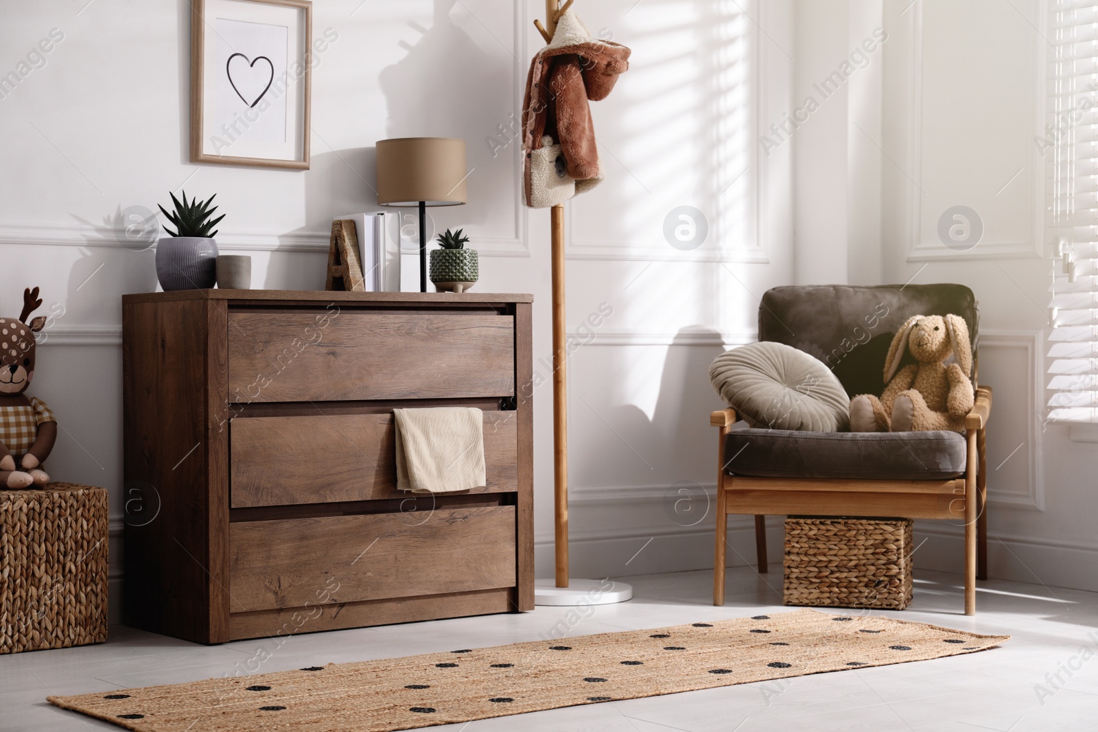 Photo of Stylish room interior with wooden chest of drawers and comfortable armchair