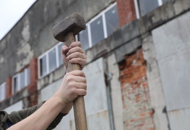 Man with sledgehammer outdoors, closeup. Space for text