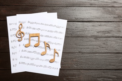 Photo of Sheets and music notes on wooden background, top view. Space for text