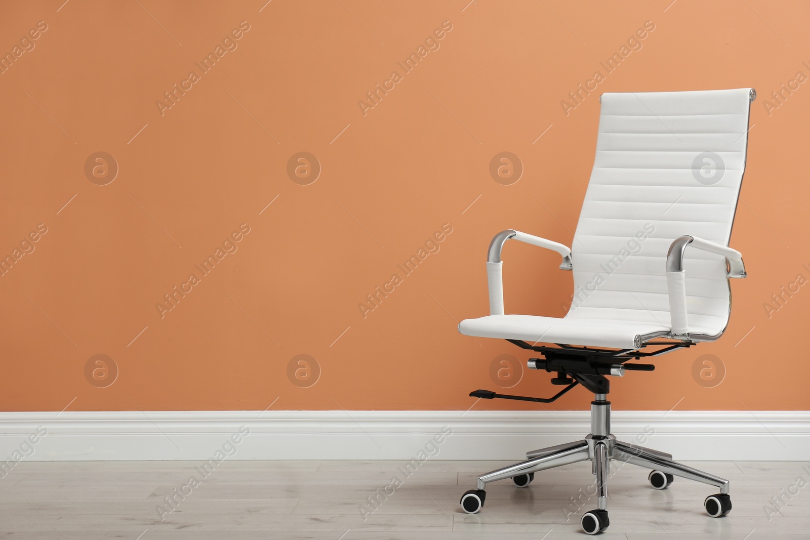 Photo of Modern office chair near orange coral wall indoors. Space for text