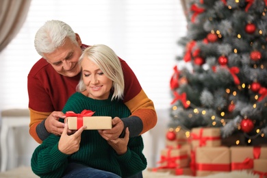 Happy mature couple with Christmas gift at home