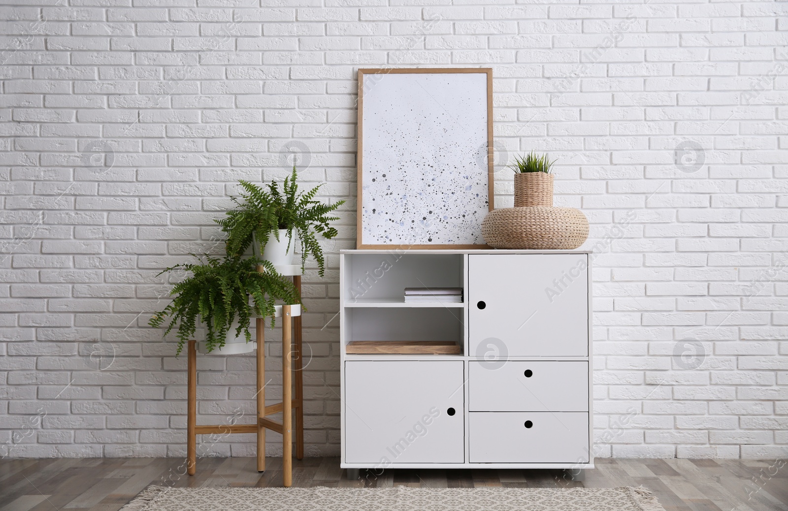 Photo of Modern white cabinet near brick wall in room. Interior design