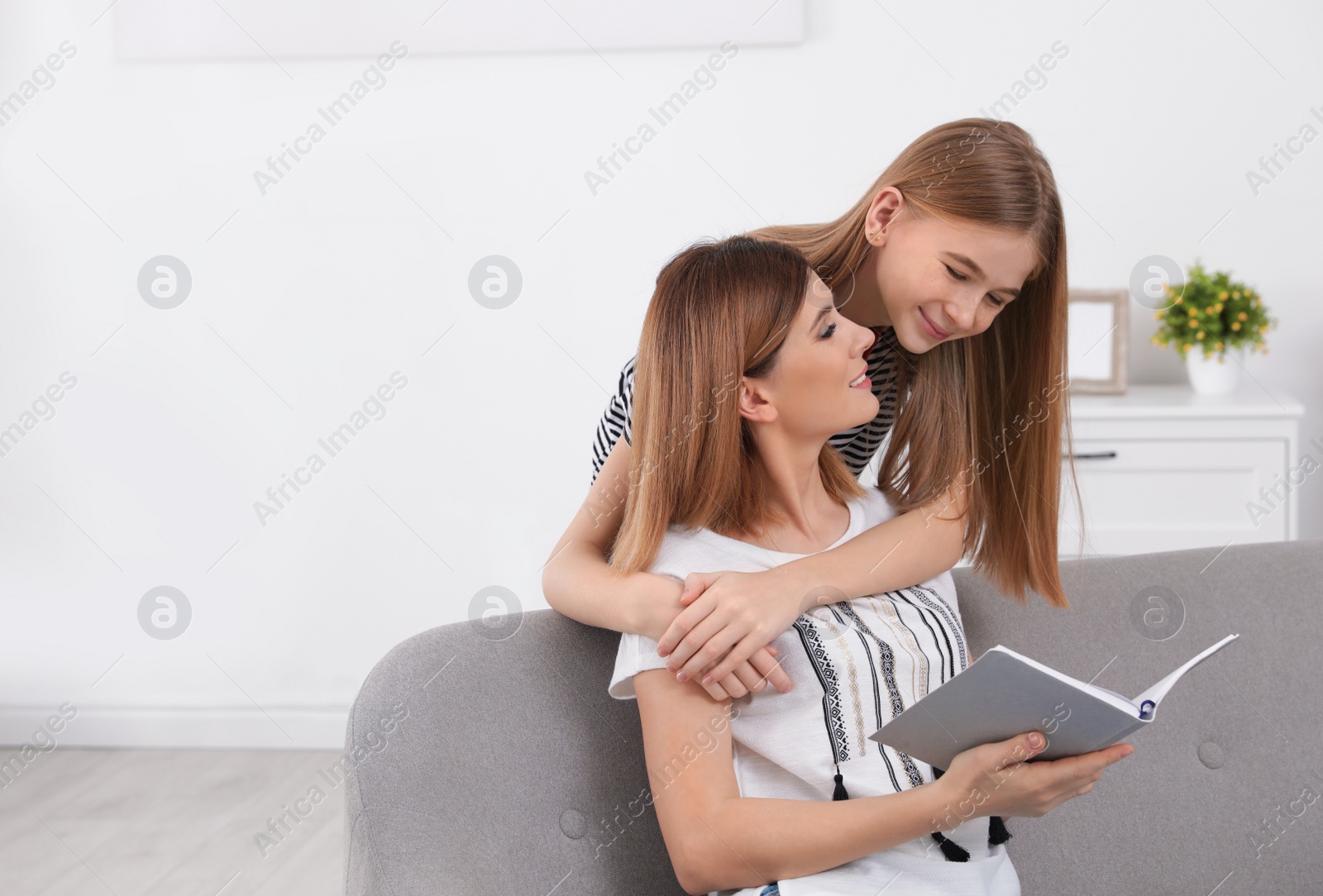 Photo of Happy mother and her teenage daughter with book at home