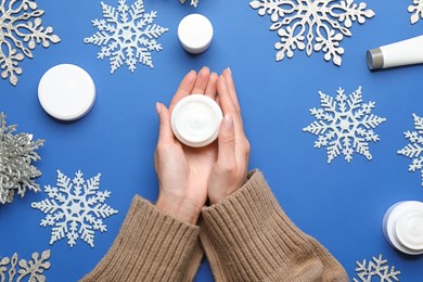 Photo of Woman with jar of hand cream on blue background, top view