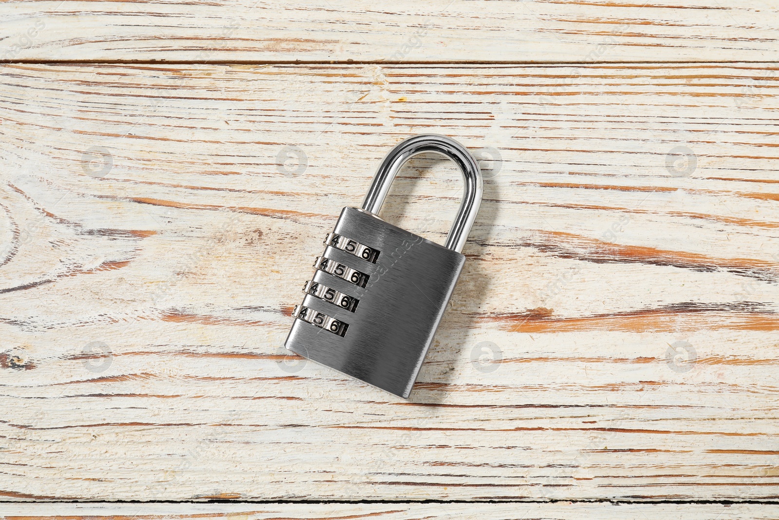 Photo of One steel combination padlock on light wooden table, top view