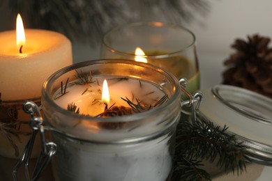 Photo of Burning scented conifer candles on table, closeup view
