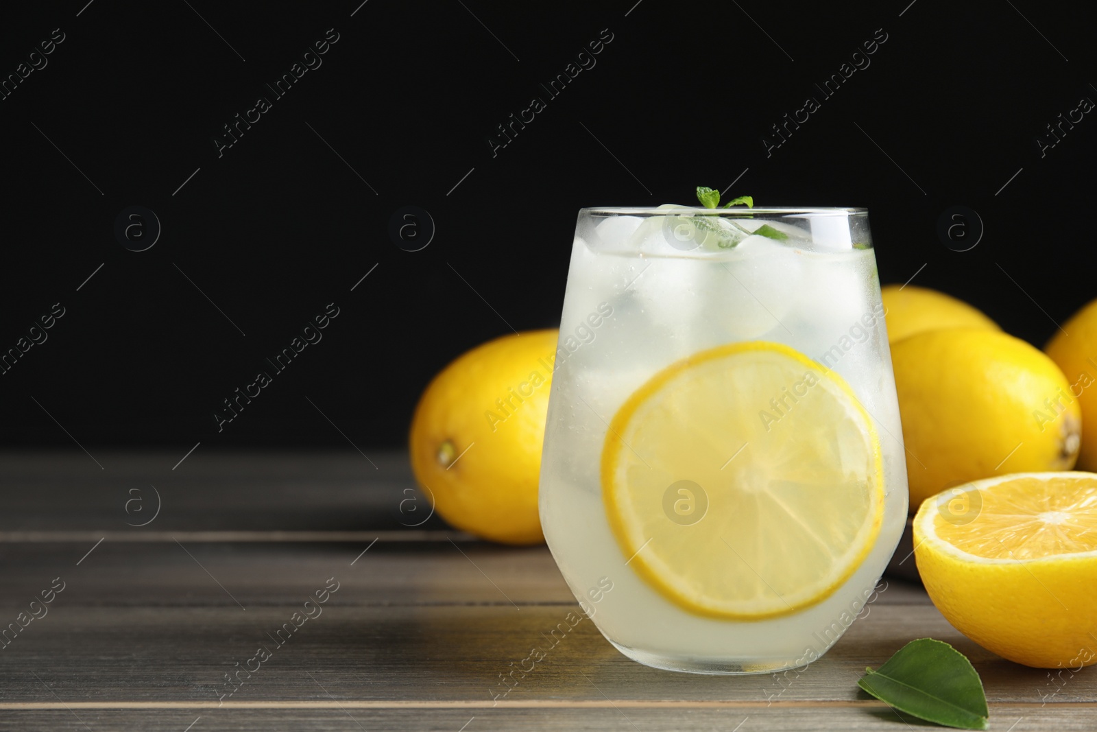 Photo of Cool freshly made lemonade and fruits on wooden table. Space for text