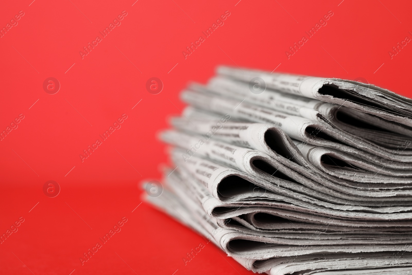 Photo of Stack of newspapers on red background, closeup. Journalist's work