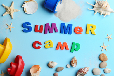 Flat lay composition with phrase SUMMER CAMP made of magnet letters on light blue background