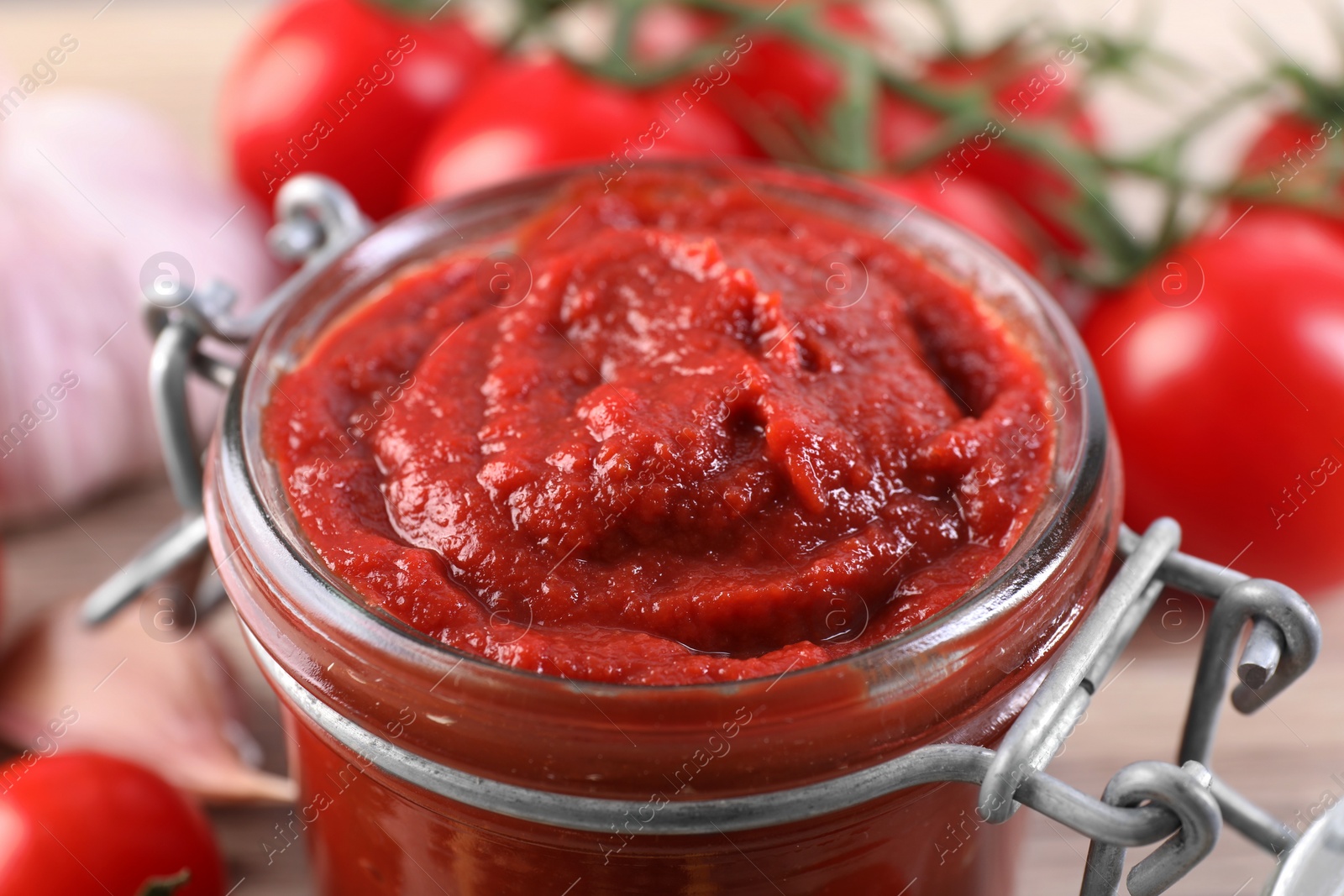 Photo of Jar of tasty tomato paste on table, closeup