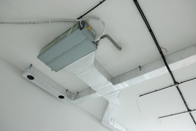 Photo of Ventilation system with pipes and wires on ceiling