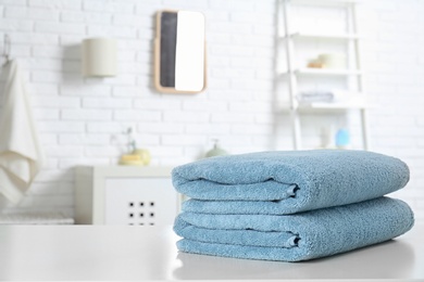 Stack of fresh towels on table in bathroom. Space for text