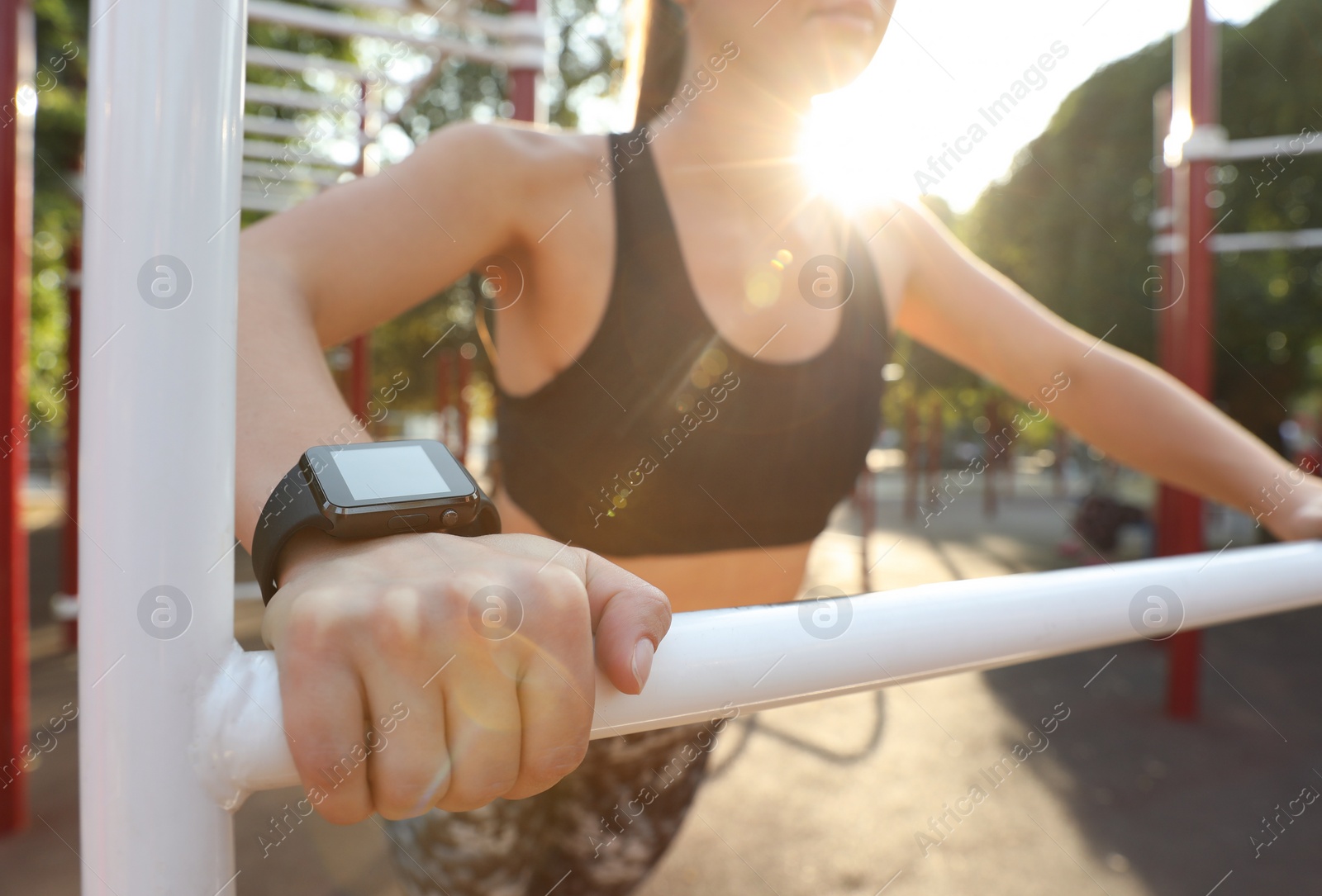 Photo of Woman wearing modern smart watch during training outdoors, closeup