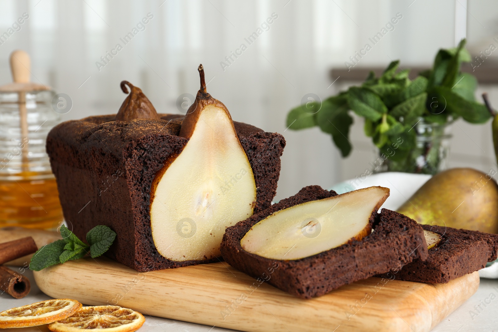 Photo of Tasty pear bread with mint, cinnamon and dried orange slices on table. Homemade cake