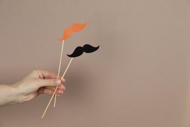 Photo of Woman with fake paper mustaches on beige background, closeup. Space for text