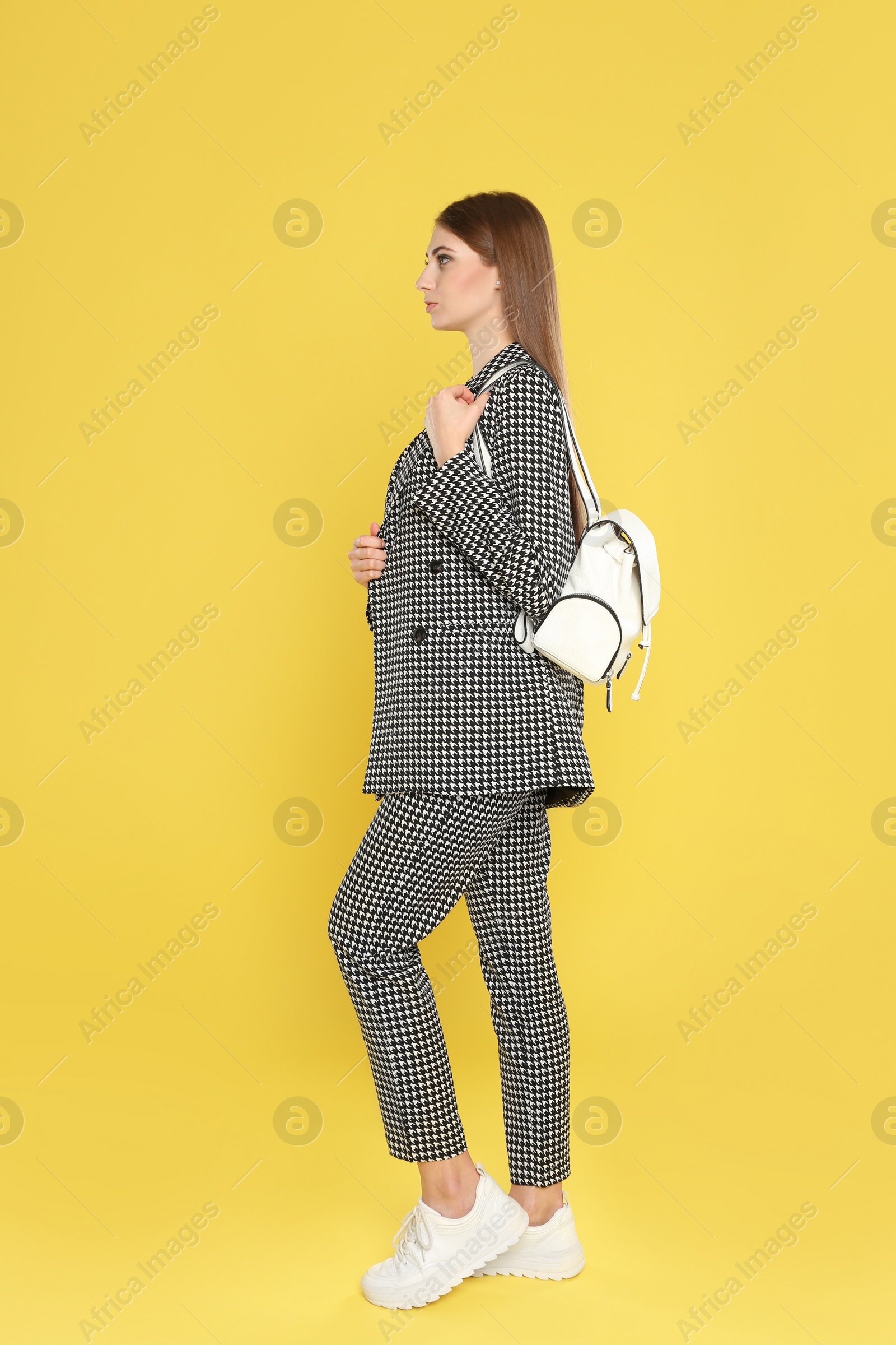 Photo of Beautiful young woman with stylish bag on yellow background