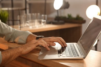 Photo of Man working with laptop at table in cafe, closeup