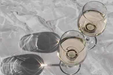 Photo of Glasses of white wine served on grey marble table, above view. Space for text