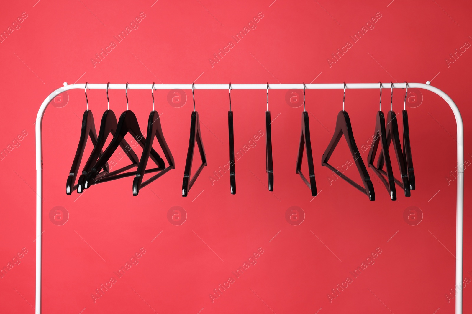 Photo of Black clothes hangers on metal rack against color background