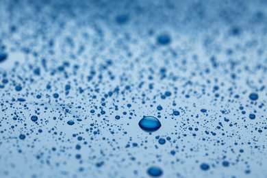 Photo of Water drops on blue background, closeup view