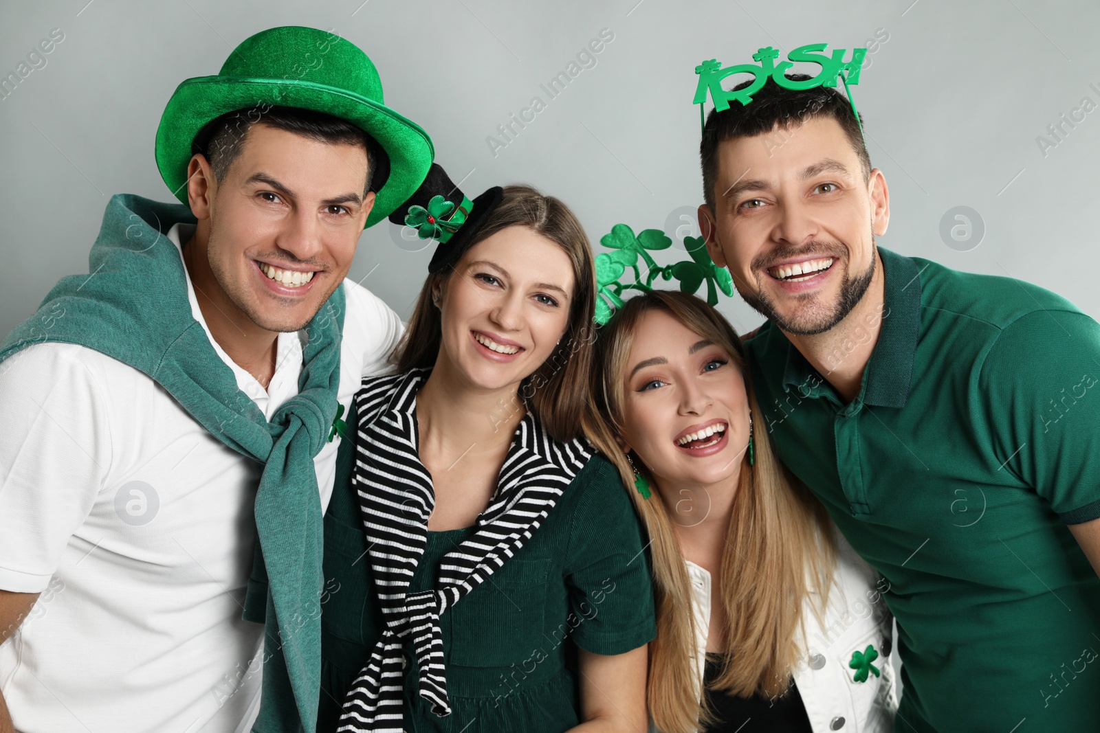 Photo of Happy people in St Patrick's Day outfits on light grey background