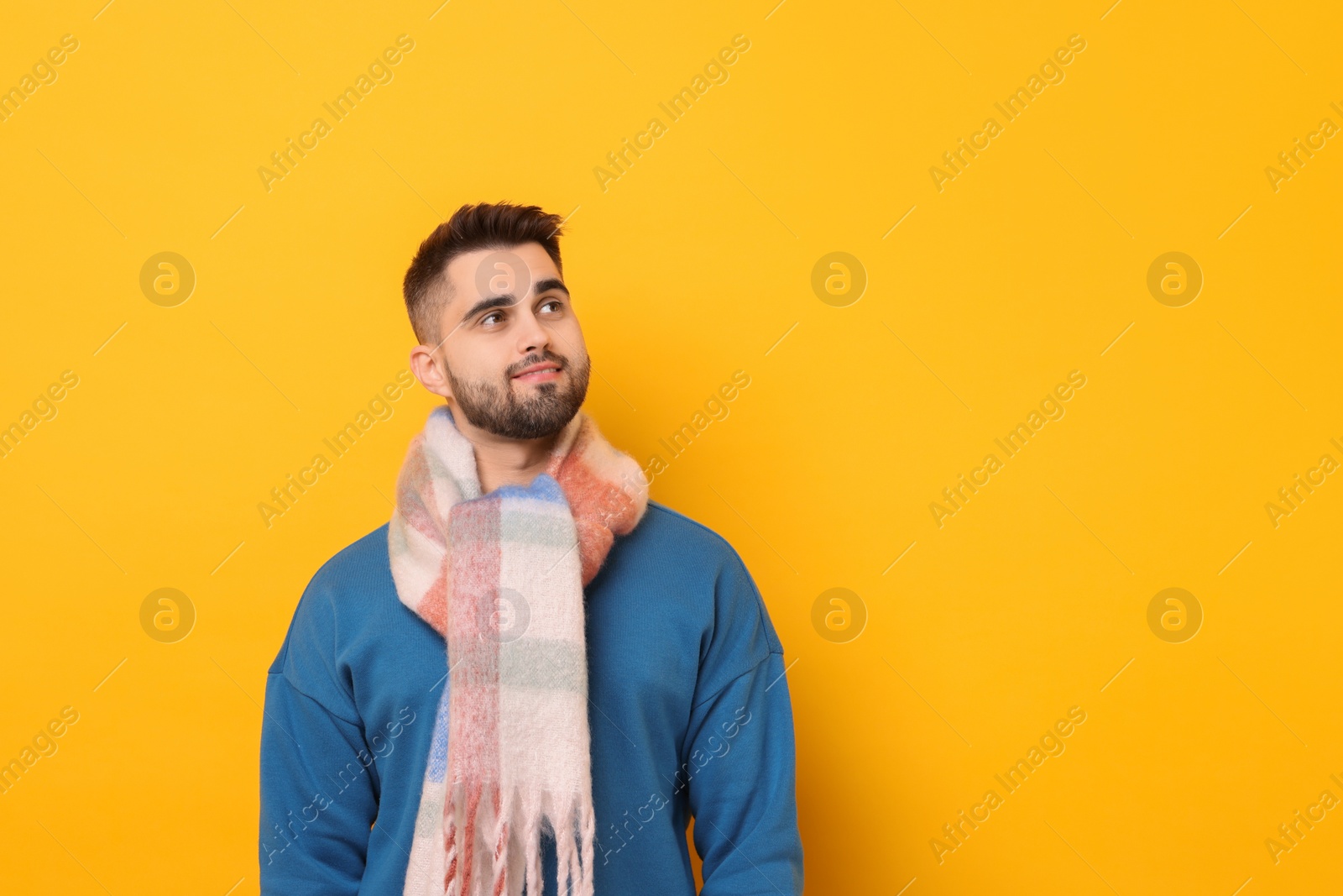 Photo of Smiling man in warm scarf on yellow background. Space for text