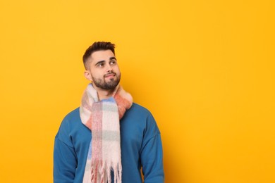 Photo of Smiling man in warm scarf on yellow background. Space for text