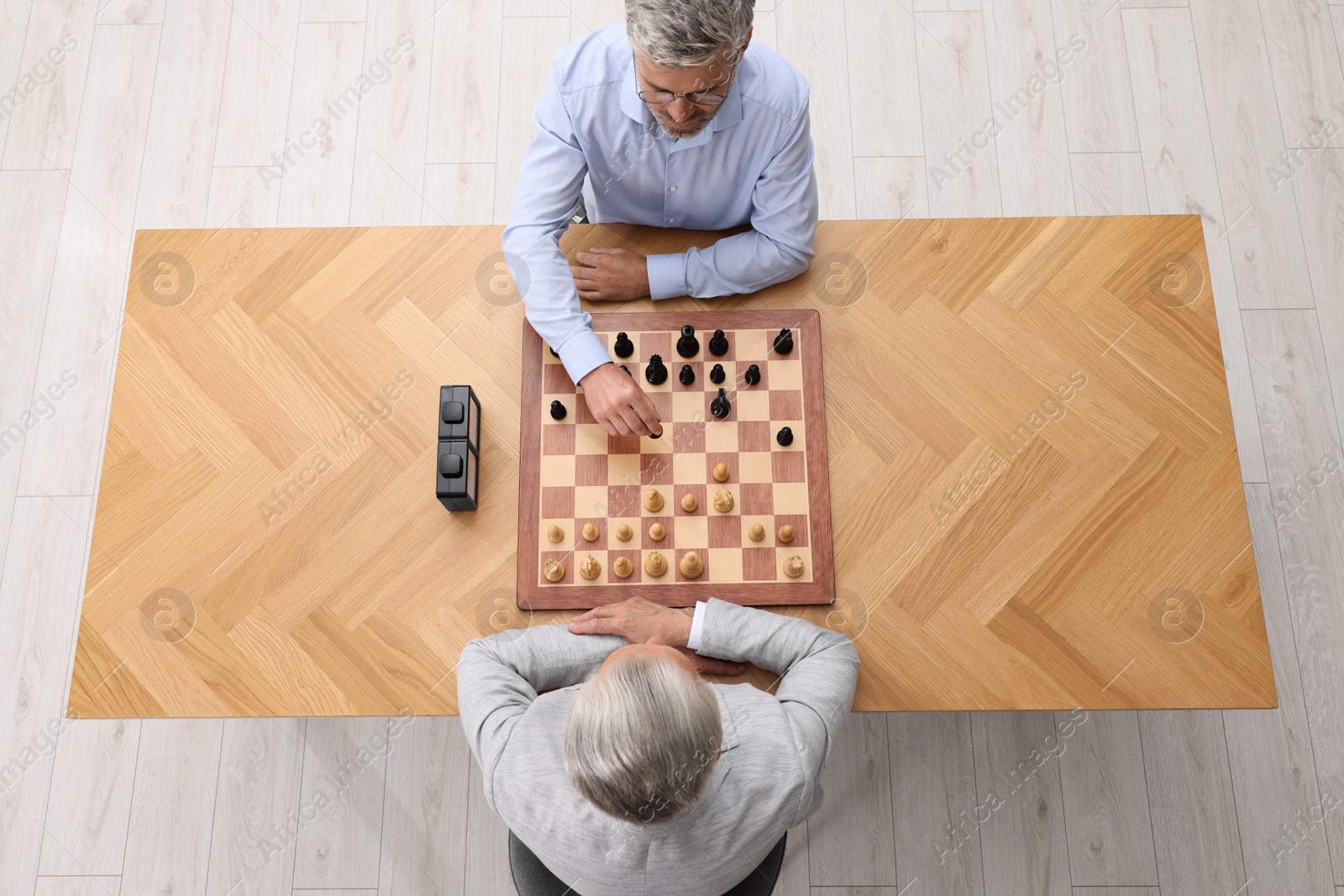 Photo of Men playing chess during tournament at wooden table, above view