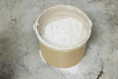 Bucket with powdered plaster and liquid on concrete floor