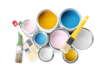 Cans of colorful paints and brushes isolated on white, top view