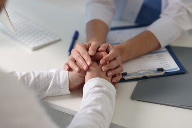 Professional doctor working with patient at white table in hospital, closeup