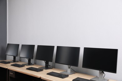 Photo of Open office interior. Modern workplaces with computers near light grey wall