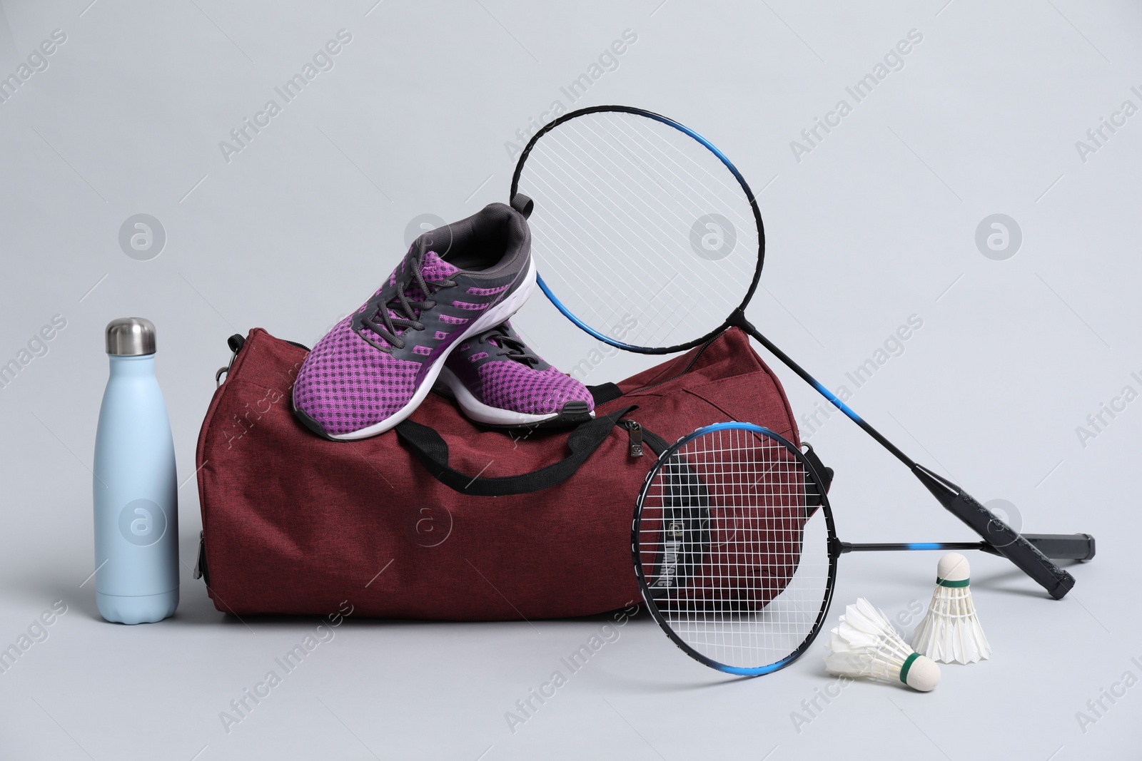 Photo of Badminton set, bag, sneakers and bottle on gray background