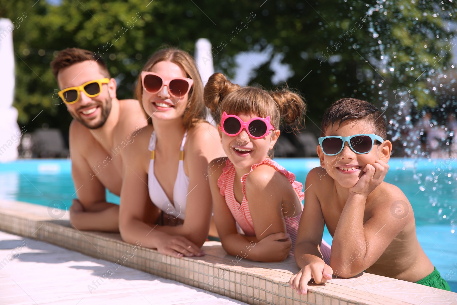 Photo of Happy family in swimming pool on sunny day