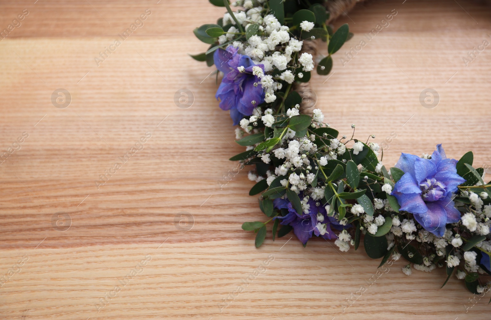 Photo of Beautiful flower wreath on wooden background, closeup. Space for text