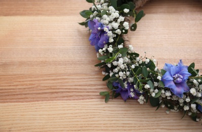 Beautiful flower wreath on wooden background, closeup. Space for text